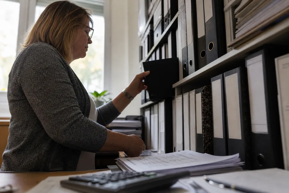 Księgowa z segregatorami rocznych sprawozdań finansowych