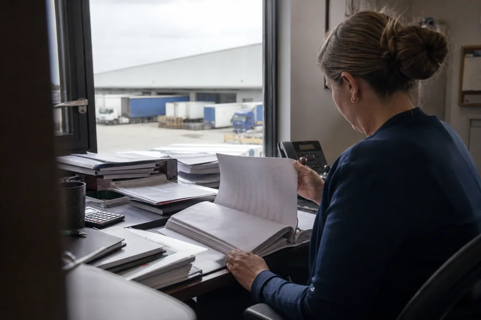 Właścicielka firmy logistycznej przegląda w biurze teczkę dokumentów swoich spółek